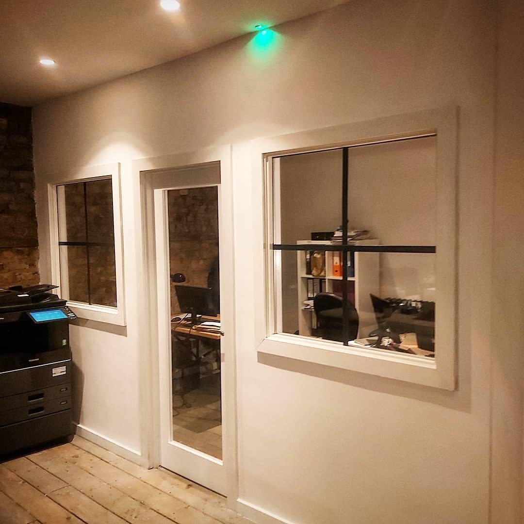 A glazed partition wall with a door and two windows into an office